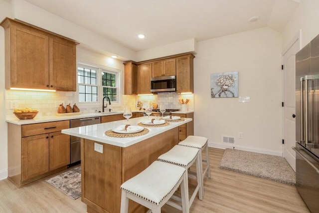 kitchen featuring a center island, appliances with stainless steel finishes, light hardwood / wood-style floors, and a breakfast bar