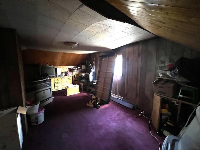 bonus room featuring wood walls, lofted ceiling, dark colored carpet, and a baseboard heating unit