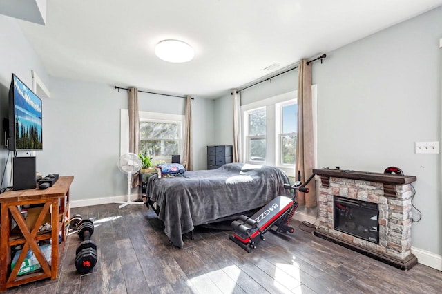 bedroom featuring a stone fireplace and dark hardwood / wood-style floors