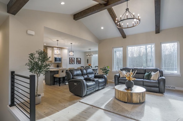 living room with high vaulted ceiling, beamed ceiling, light hardwood / wood-style flooring, and an inviting chandelier