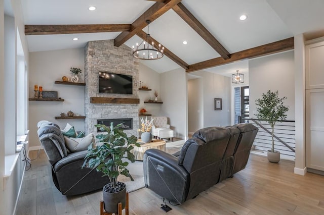 living room featuring light hardwood / wood-style floors, lofted ceiling with beams, a stone fireplace, and a chandelier