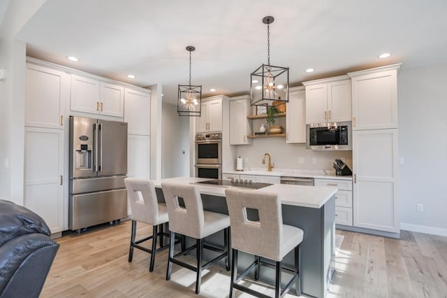 kitchen with a kitchen island, light hardwood / wood-style flooring, pendant lighting, white cabinetry, and appliances with stainless steel finishes