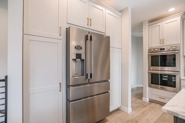 kitchen featuring light hardwood / wood-style flooring, white cabinets, light stone countertops, and stainless steel appliances