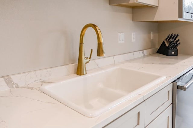 interior details featuring sink, white cabinetry, and dishwasher