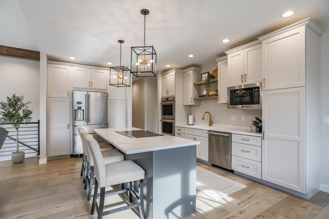 kitchen with hanging light fixtures, sink, a center island, appliances with stainless steel finishes, and light hardwood / wood-style floors