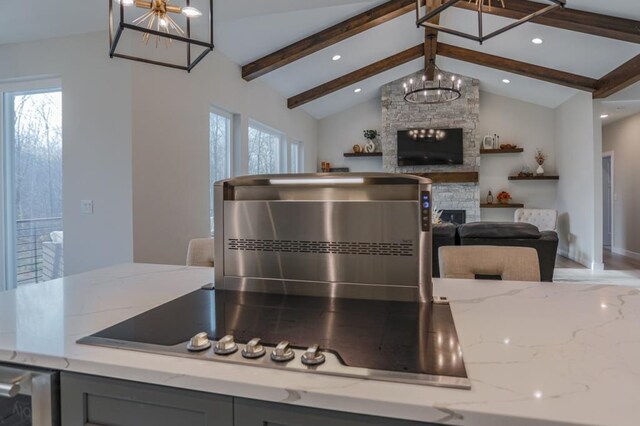 kitchen featuring light stone counters, lofted ceiling with beams, plenty of natural light, and a fireplace