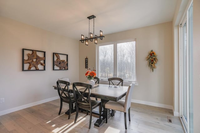 dining space featuring light hardwood / wood-style floors and a notable chandelier