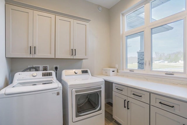 laundry room featuring hardwood / wood-style floors, washing machine and dryer, and cabinets