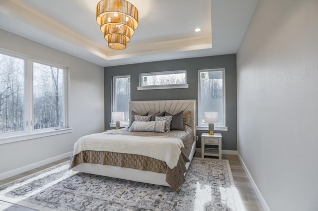 bedroom featuring a notable chandelier, a tray ceiling, and hardwood / wood-style floors