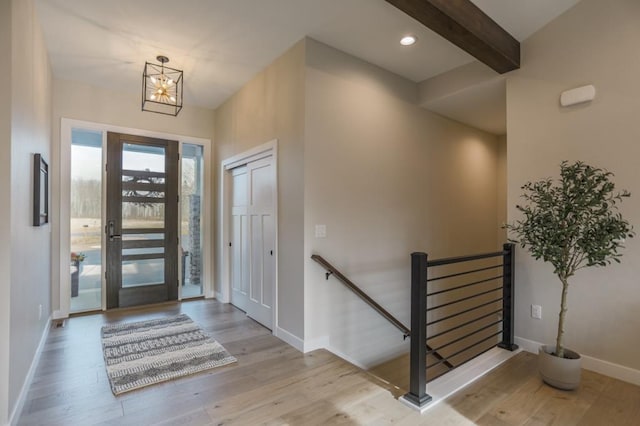 entryway with beam ceiling, a chandelier, and light hardwood / wood-style flooring