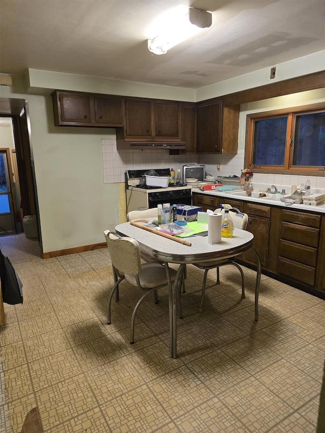 kitchen with custom range hood, decorative backsplash, dark brown cabinetry, and gas range gas stove