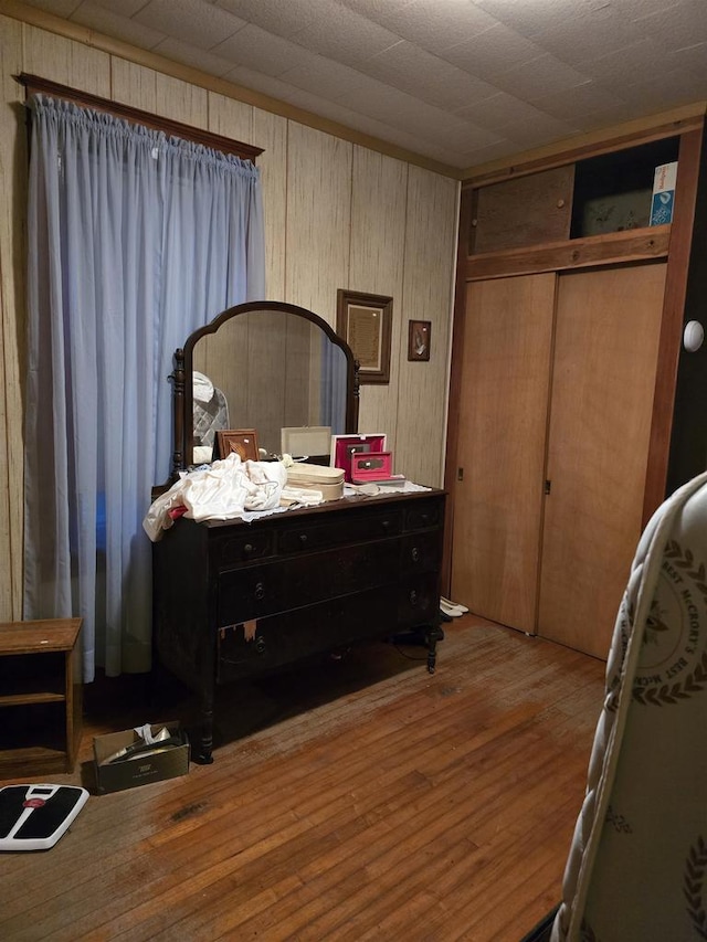 bedroom featuring a closet, hardwood / wood-style floors, and wooden walls