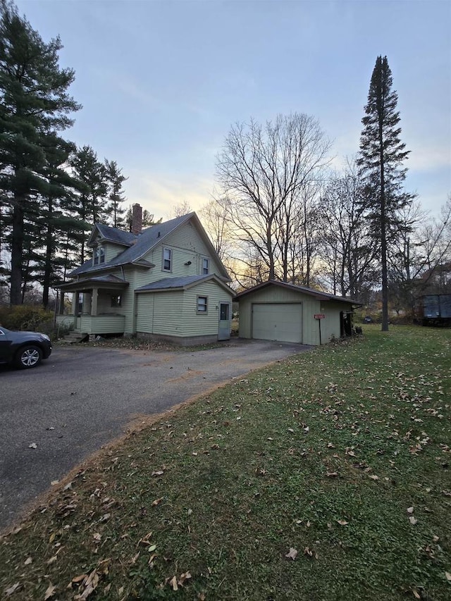 exterior space with a yard, a garage, and an outbuilding