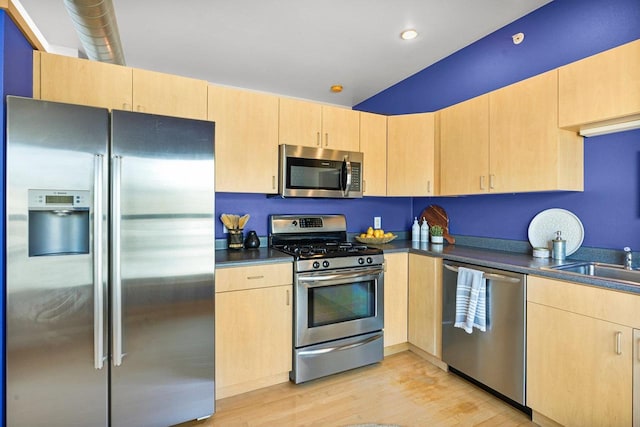 kitchen featuring appliances with stainless steel finishes, sink, light brown cabinetry, and light wood-type flooring