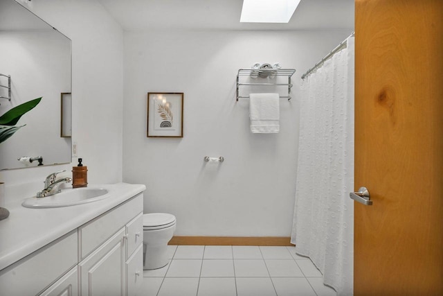 bathroom featuring vanity, toilet, a skylight, and tile patterned flooring