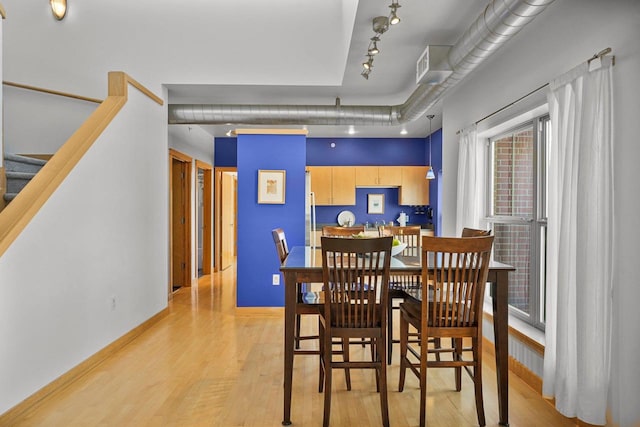 dining space with track lighting and light wood-type flooring