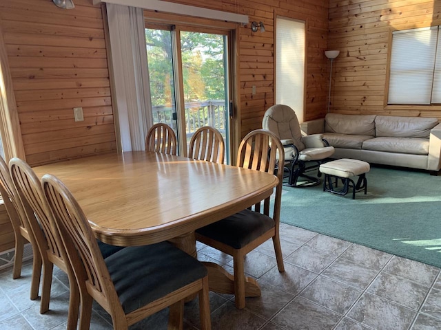 dining area featuring tile patterned floors and wooden walls