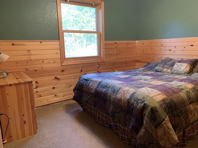 carpeted bedroom featuring wood walls