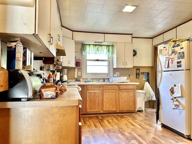 kitchen with white fridge, light hardwood / wood-style floors, and crown molding