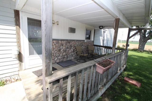 wooden terrace with a lawn and covered porch