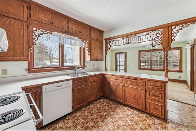 kitchen featuring sink, kitchen peninsula, and white appliances