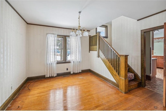 interior space featuring ornamental molding, hardwood / wood-style floors, and a notable chandelier