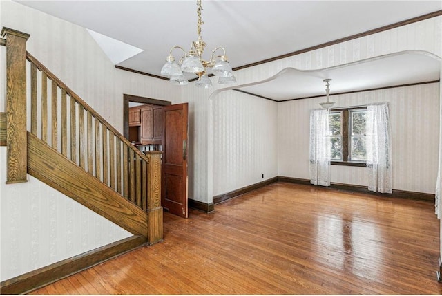 interior space with an inviting chandelier, ornamental molding, and hardwood / wood-style flooring