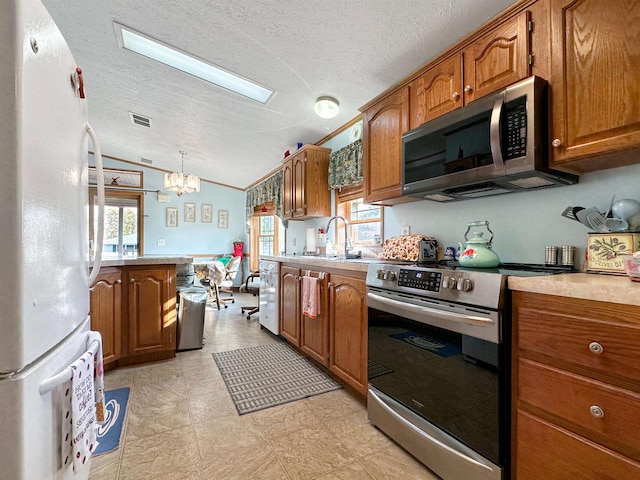 kitchen with a notable chandelier, a healthy amount of sunlight, appliances with stainless steel finishes, and hanging light fixtures