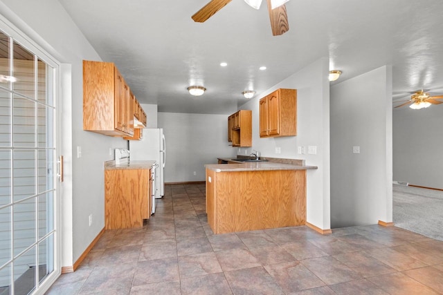 kitchen with kitchen peninsula, sink, light tile patterned floors, stove, and ceiling fan