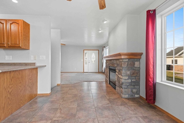 unfurnished living room featuring a stone fireplace and light tile patterned flooring