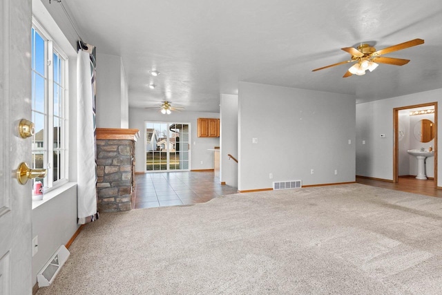 unfurnished living room with light carpet, a wealth of natural light, and ceiling fan