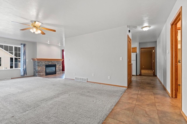 unfurnished living room with ceiling fan, light tile patterned floors, and a fireplace