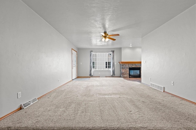 unfurnished living room with a stone fireplace, carpet flooring, and ceiling fan