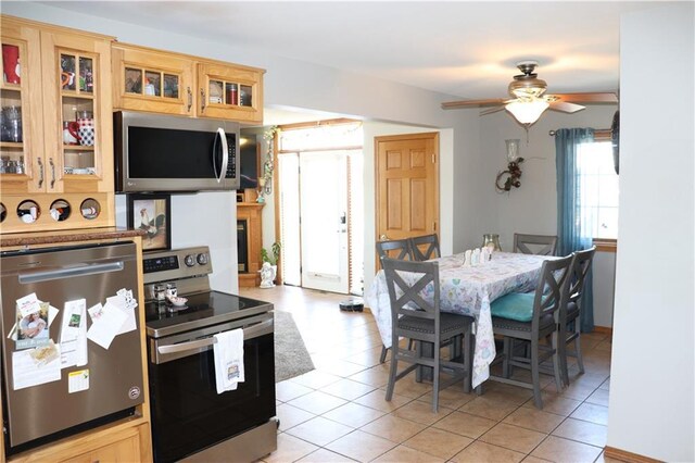 kitchen featuring ceiling fan, stainless steel appliances, and light tile patterned flooring