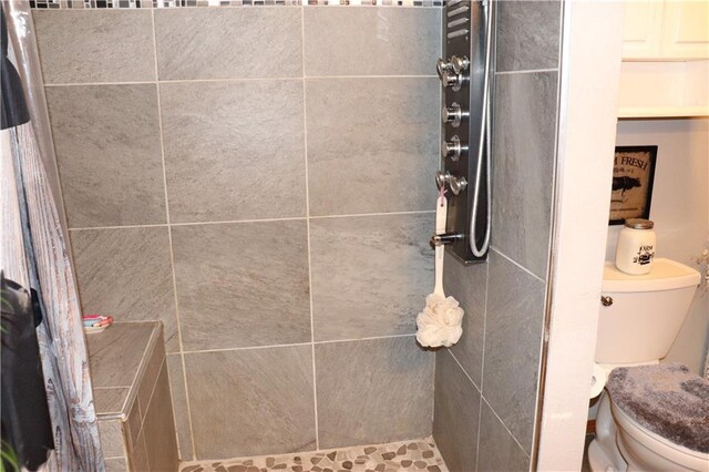 bathroom featuring toilet and tiled shower