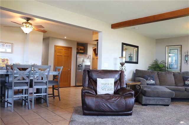 living room with beam ceiling, light tile patterned flooring, and ceiling fan