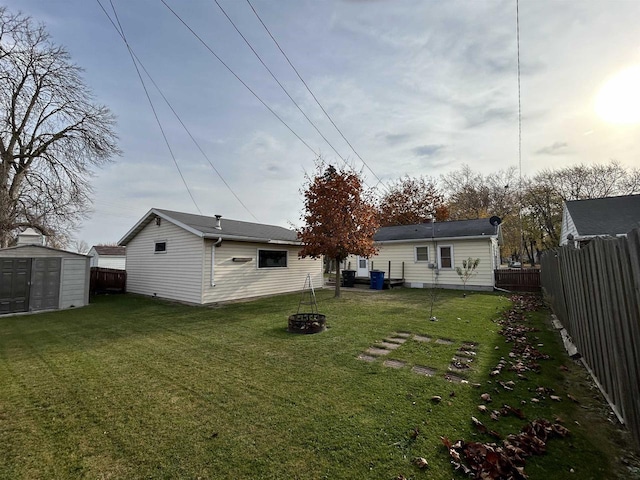 rear view of house featuring a yard, a shed, and a fire pit