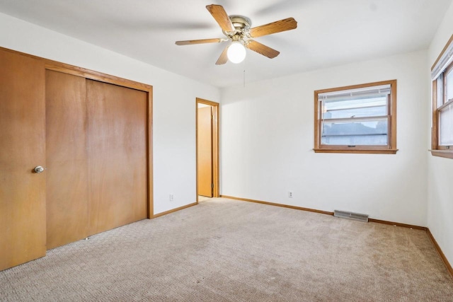 unfurnished bedroom with light carpet, a closet, and ceiling fan