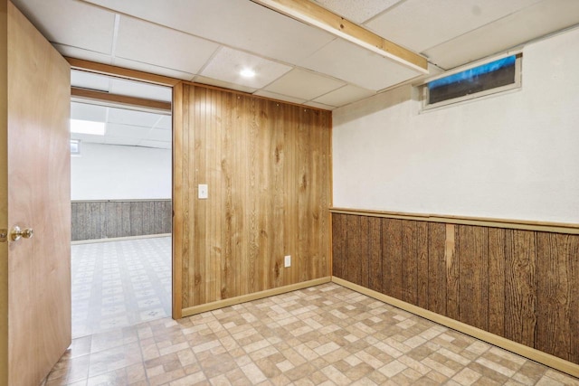 empty room with a paneled ceiling and wooden walls