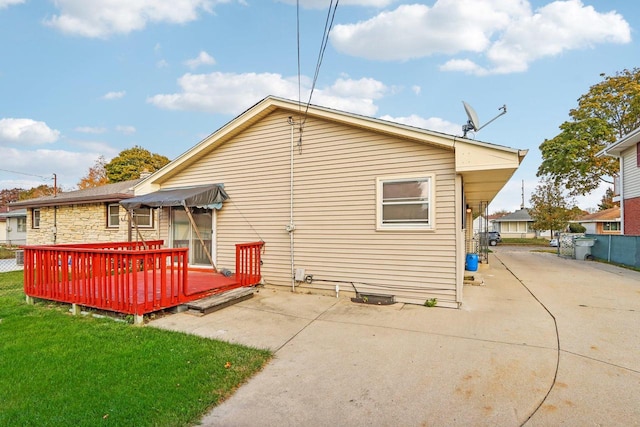 rear view of property with a patio, a wooden deck, and a lawn