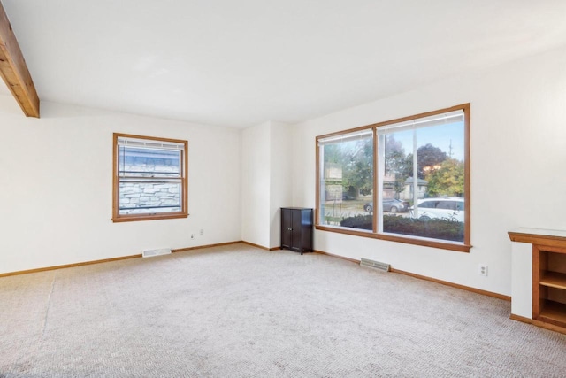 spare room with beam ceiling and light colored carpet