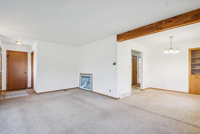 spare room with beam ceiling, a chandelier, and light colored carpet