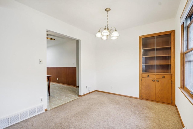 empty room featuring light carpet and an inviting chandelier