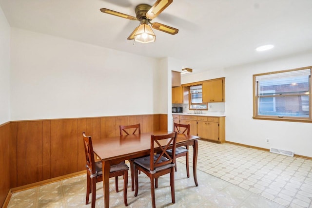 dining area featuring wooden walls, sink, and ceiling fan