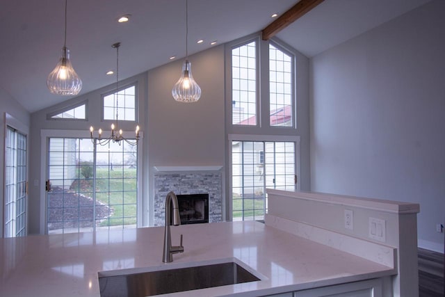 kitchen with beamed ceiling, sink, hanging light fixtures, and a fireplace