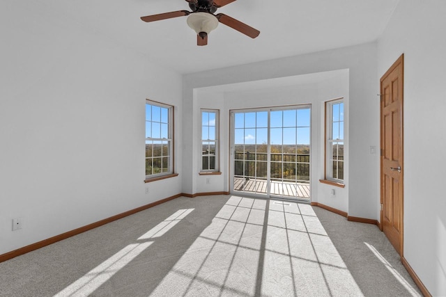 spare room featuring light colored carpet, ceiling fan, and a healthy amount of sunlight