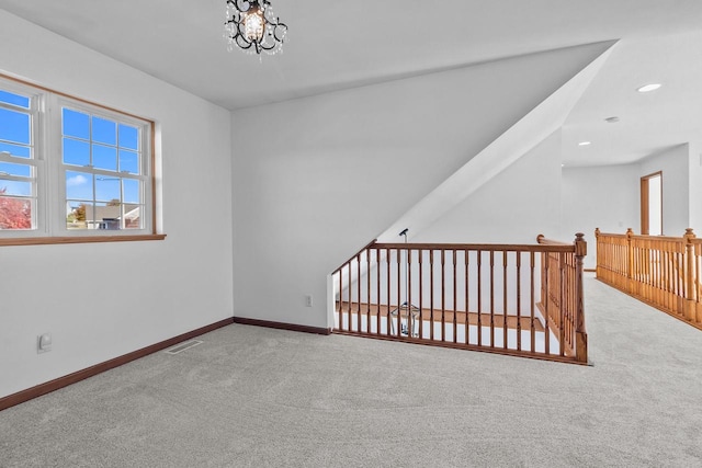 carpeted spare room with a chandelier