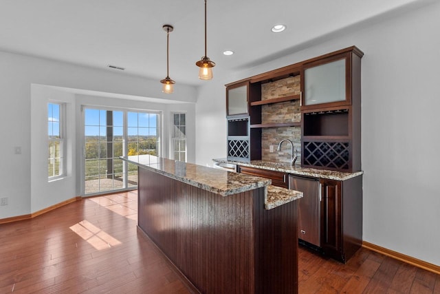 bar featuring decorative light fixtures, dishwasher, dark brown cabinets, and dark hardwood / wood-style floors