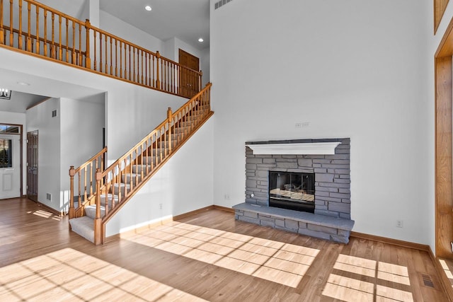 unfurnished living room with a high ceiling, light hardwood / wood-style flooring, and a stone fireplace