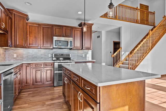 kitchen featuring light hardwood / wood-style flooring, pendant lighting, a center island, stainless steel appliances, and tasteful backsplash